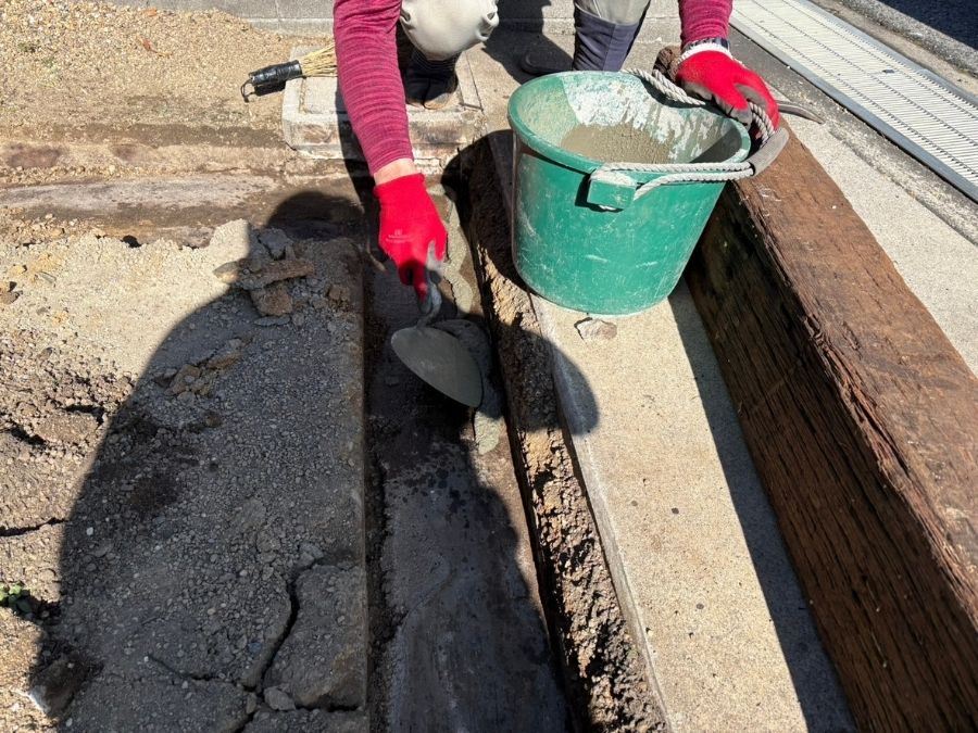 堺市中区の駐車場で天然枕木をコンクリートで固定する施工中の様子