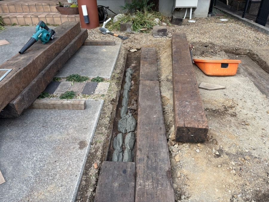 堺市中区の駐車場で天然枕木をコンクリートで固定する施工中の様子