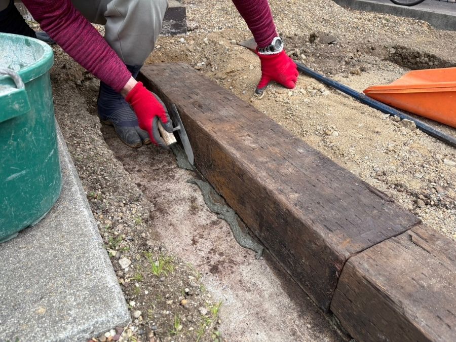 堺市中区の駐車場で天然枕木をコンクリートで固定する施工中の様子